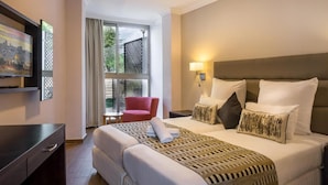 Habitación de hotel con cama, televisión, escritorio, silla y ventana con vistas a zonas verdes.