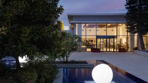 Un edificio moderno con amplios ventanales de vidrio, un jardín cuidado y una llamativa esfera luminosa.