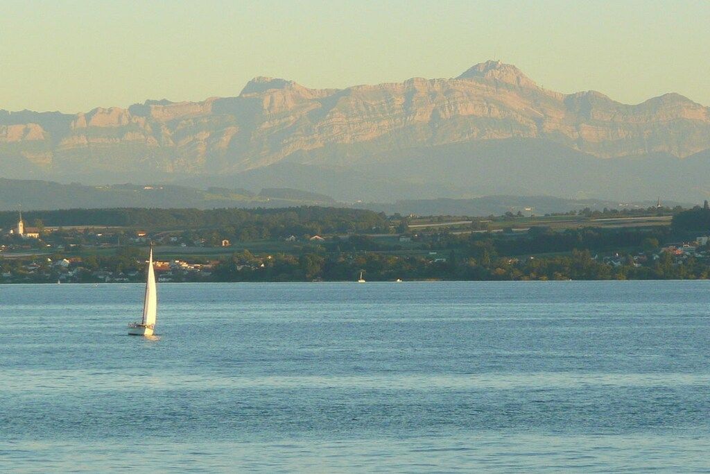 A sailboat on calm water with mountains in the background.