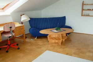 A room with a desk, chair, sofa, and a small table with a lamp. - Holiday apartment with 1 bedroom (Konstanz)