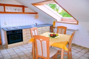 A compact kitchen with a dining area, including a table with chairs and a fruit bowl. - Holiday apartment with 1 bedroom (Konstanz)