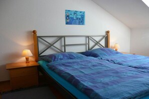 A single bed with a wooden headboard, a nightstand with a lamp, and a wall-mounted picture. - Holiday apartment with 1 bedroom (Konstanz)