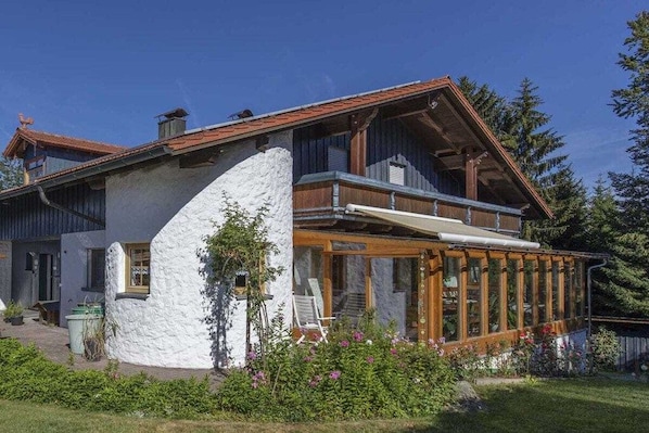 Et toetagers hus med balkon, stenvæg og en blomsterprydet have.