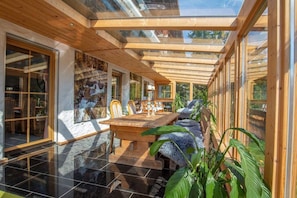 Et moderne interiør med spiseplads, træloft og store vinduer.