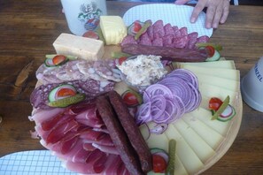 Tábua de frios com diversos tipos de carne, queijos e legumes.