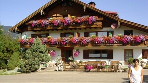 Een klassiek chalet met meerdere balkons versierd met kleurrijke bloemen, een houten hek en een heldere lucht.