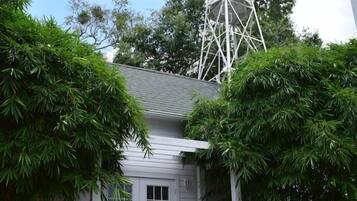 A house with a windmill, surrounded by greenery and a small porch.