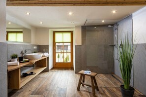 A modern bathroom with a large bathtub, a shower area, and a wooden vanity with a sink. - Unterbrandnerlehen Apart Chalet Watzmann (Königssee)