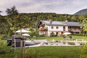 A large house with a solar panel roof, a swimming pool, and a garden with lounge chairs. - Unterbrandnerlehen Apart Chalet Watzmann (Königssee)