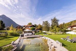 A mountain resort with a swimming pool, lounge chairs, and a view of the mountains. - Unterbrandnerlehen Apart Chalet Watzmann (Königssee)