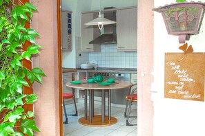 Een keuken met een ronde tafel, stoelen, een fornuis en een hanglamp.