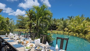 A dining table set for a meal with a poolside view. - La Cigale Estate (Anse Volbert Village)