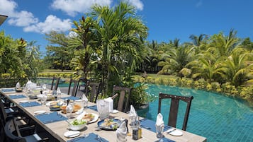 Mesa de comedor lista para una comida, con vista a la piscina.