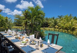 A dining table set for a meal with a poolside view. - La Cigale Estate (Anse Volbert Village)