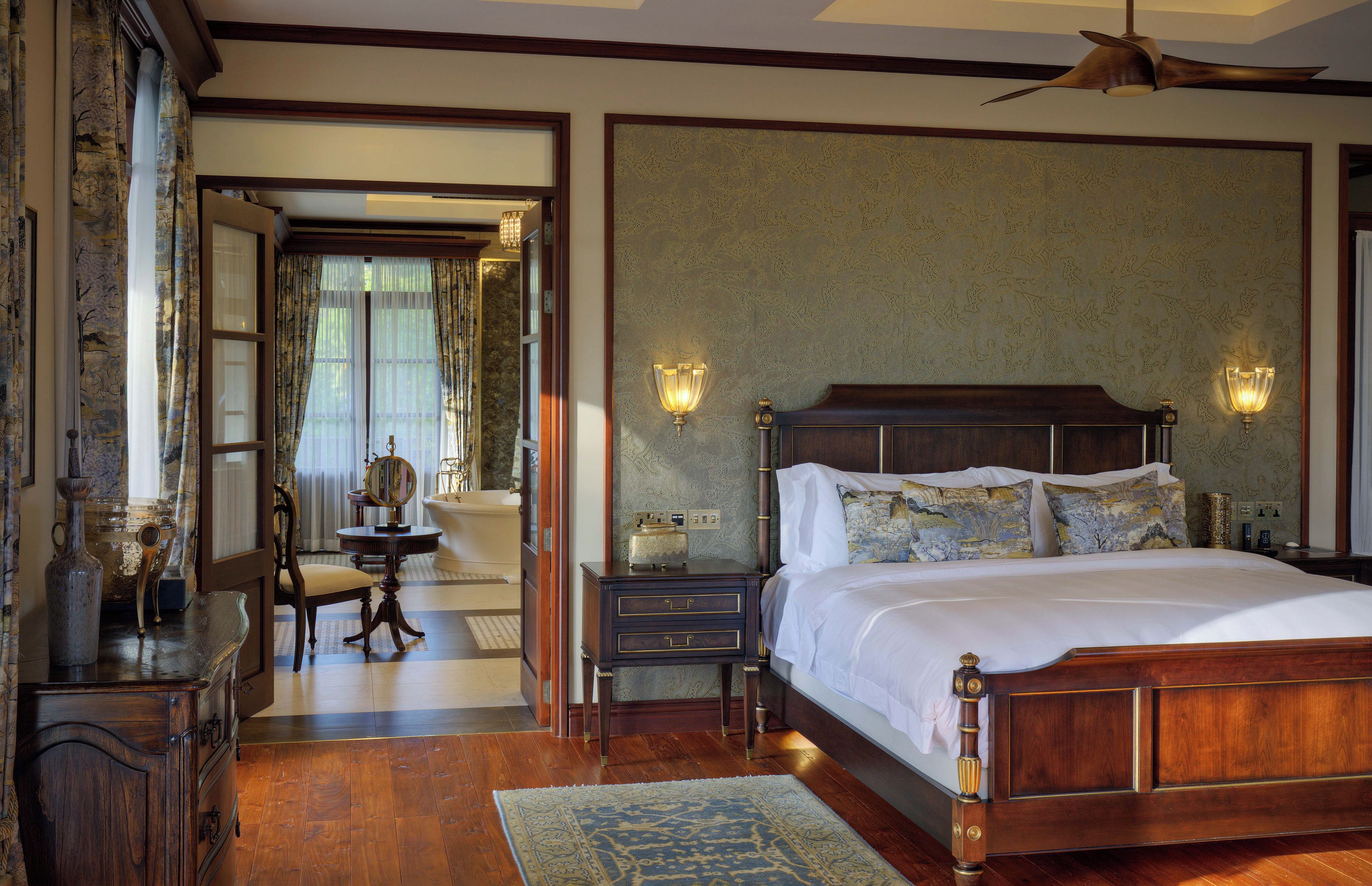A traditional bedroom with a wooden bed, two bedside lamps, a nightstand, a dresser, and a mirror.