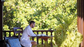 Una persona sentada a una mesa con vistas a vegetación exuberante y una estructura de pérgola.
