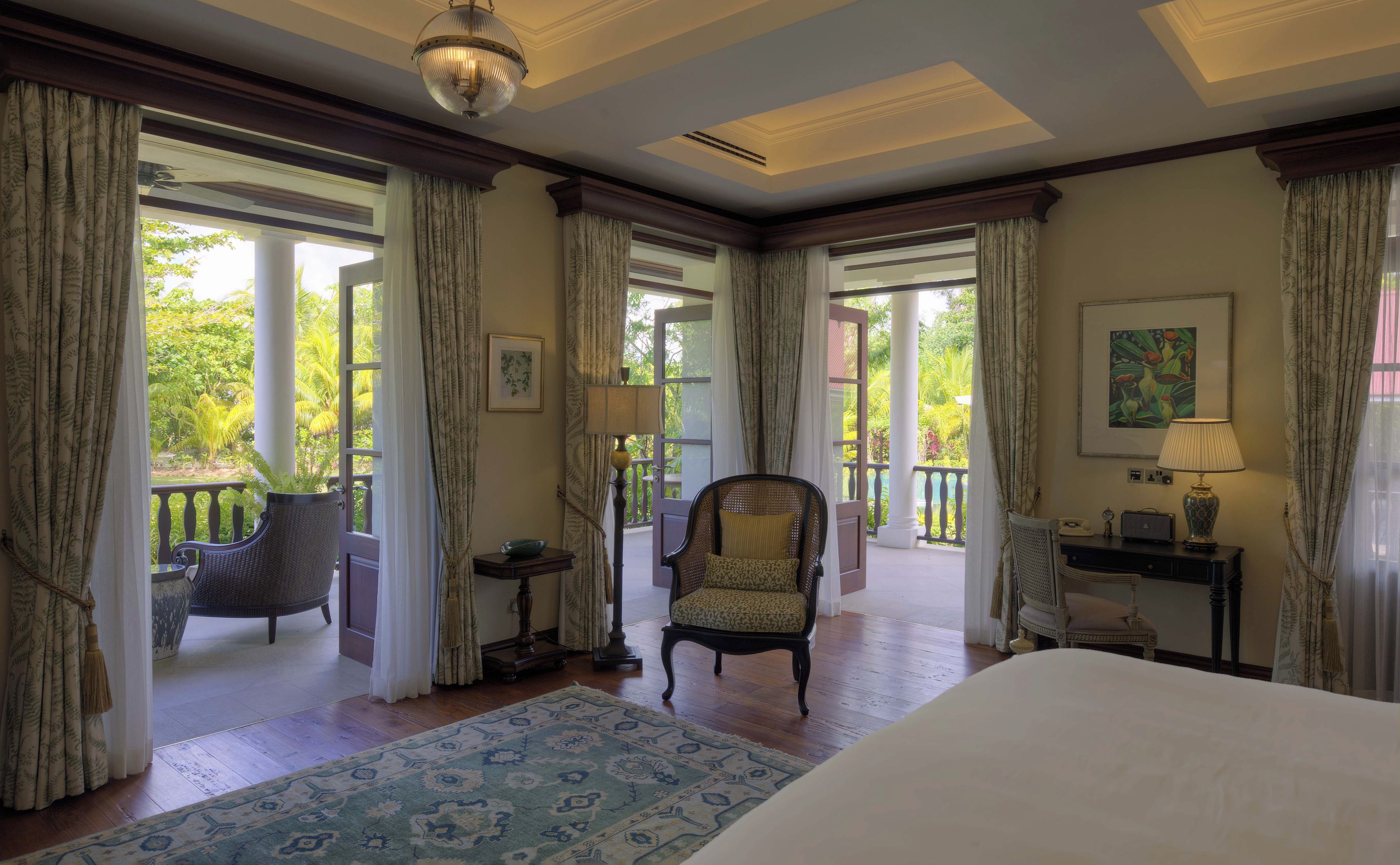 Habitación de hotel con una cama grande, dos sillones, un escritorio con lámpara y vistas al exterior.