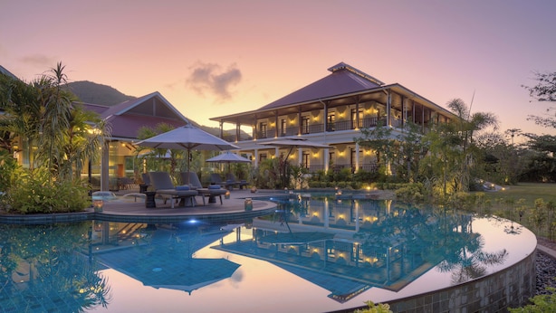 A resort with a swimming pool, lounge chairs, and a large building with multiple balconies. - La Cigale Estate (Anse Volbert Village)