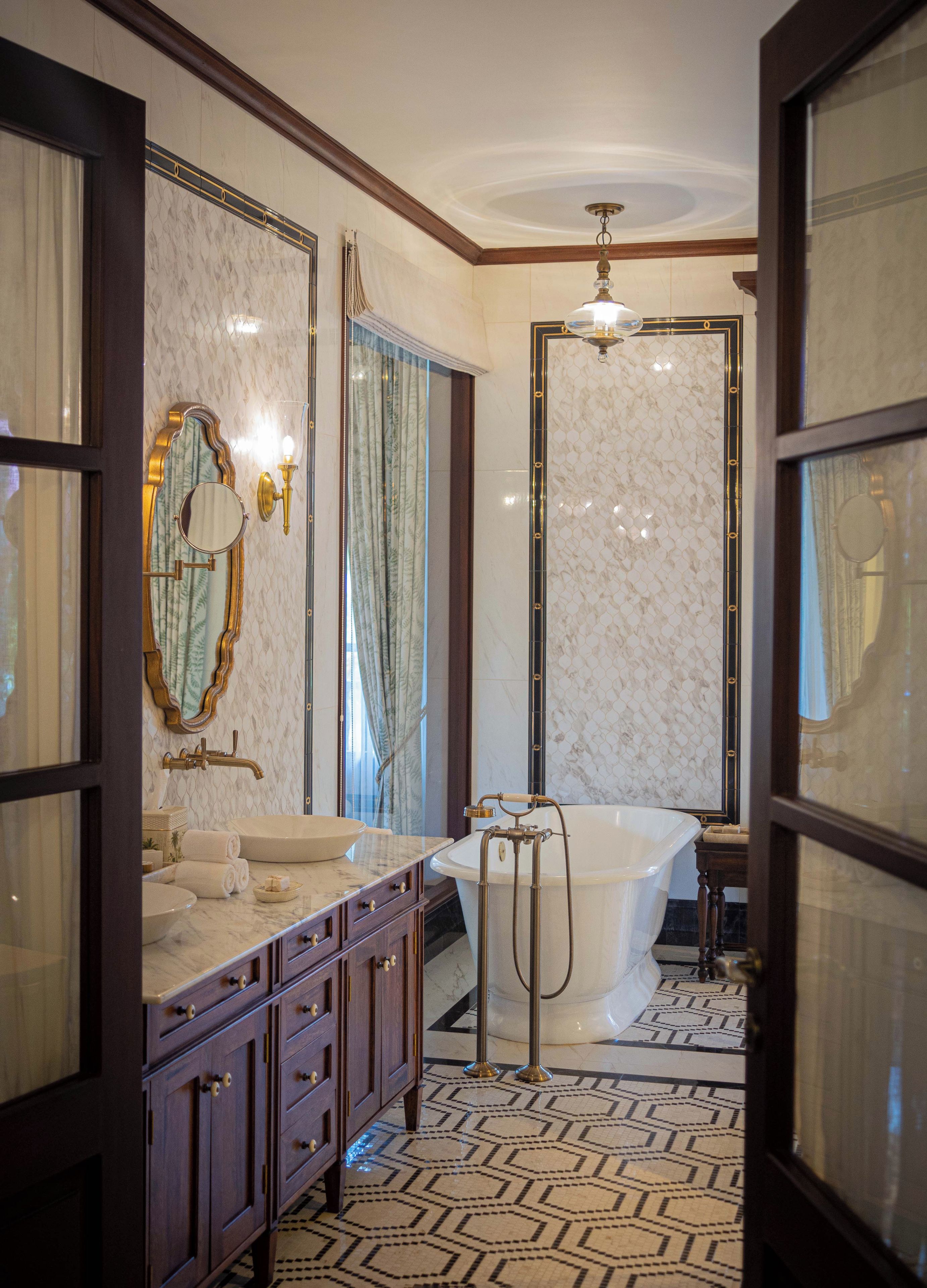 A bathroom with a marble vanity, a freestanding bathtub, and a large mirror.
