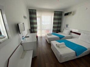 A hotel room with two beds, a desk, a chair, a TV, and a window with curtains. - Hotel Phenicia Marina (Finike)