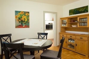 Un comedor con una mesa redonda, sillas y un cuadro de girasoles.