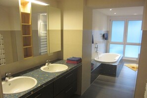 Casa de banho moderna com duas pias, um espelho grande e área de duche separada.