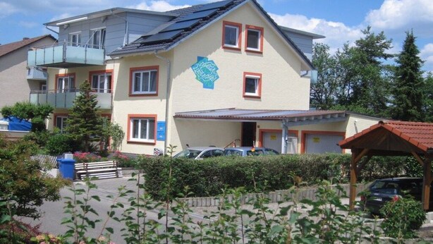 A multi-story residential building with a balcony, a garage, and a covered parking area. - Rolf Bauer on the 1st floor (Konstanz)