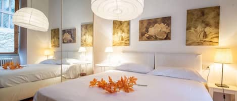 A hotel room with a large bed, two bedside tables, a mirror, and artwork on the walls.