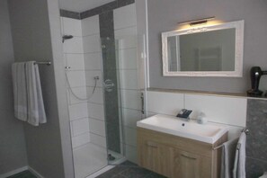 Un bagno con doccia, lavandino e specchio.