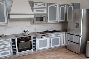 A modern kitchen with a stainless steel refrigerator, built-in oven, microwave, and a kettle on the countertop. - Holiday apartment with 1 bedroom (Willingen-Usseln)