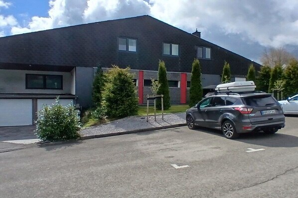 Un edificio moderno su due piani con tetto grigio, garage e vialetto.