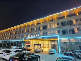 Um hotel com vários andares, um amplo estacionamento e uma entrada bem iluminada.