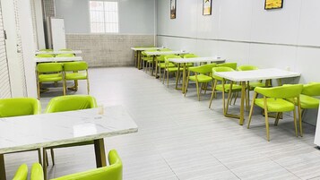 A dining area with multiple tables and chairs, a tiled backsplash, and a window providing natural light.