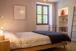 A bedroom with a bed, a window, a shelf with items, and a wall-mounted light fixture. - Holiday home in Treserve with Wi-Fi (Tresserve)