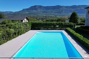 A rectangular swimming pool with a clear blue water surface, surrounded by a paved deck and bordered by neatly trimmed hedges. - Holiday home in Treserve with Wi-Fi (Tresserve)