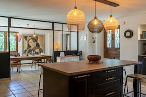 A kitchen with a large island, pendant lights, and a dining area with chairs and a table. - Holiday home in Treserve with Wi-Fi (Tresserve)
