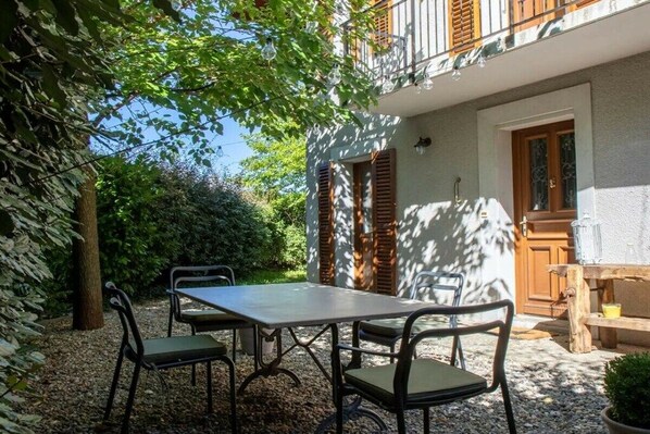 A patio with a table and chairs, a wooden door, and a balcony with railings. - Holiday home in Treserve with Wi-Fi (Tresserve)