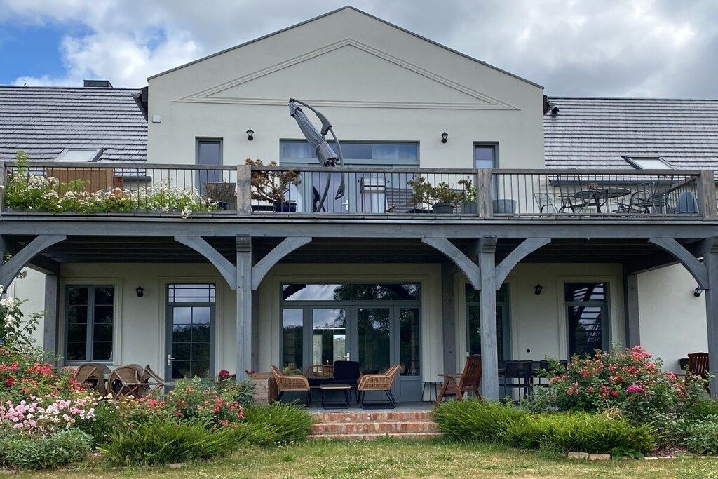 Un bâtiment à deux étages doté d’un balcon, d’un espace extérieur aménagé pour s’asseoir et d’un jardin.