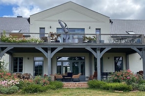 A two-story building with a balcony, outdoor seating, and a garden. - Erbschulzenhof (Müritz) (Buchholz (Müritz))