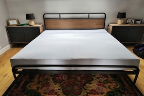 A single bed with a metal frame and wooden headboard, flanked by two bedside tables with lamps, in a room with hardwood flooring. - Erbschulzenhof (Müritz) (Buchholz (Müritz))