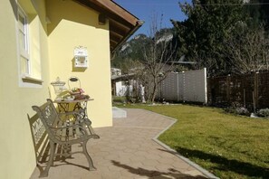 Ein gelbes Gebäude mit einer Terrasse, einer Bank und einem Tisch mit Gegenständen darauf.
