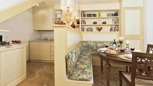A cozy kitchen with a built-in bench, wooden cabinets, and a dining area with a table set for two.