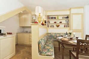 A cozy kitchen with a built-in bench, wooden cabinets, and a dining area with a table set for two.
