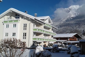 Hotel com vários andares e varandas, com uma pista de esqui ao fundo e uma paisagem montanhosa.
