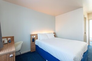 Una habitación de hotel con una cama, un escritorio y una silla.
