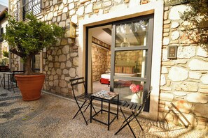 A stone building with a large potted tree, a small table, and two chairs outside. - Fiore Garden Suites (Antalya)