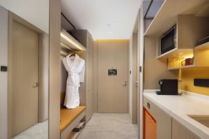 A hotel room with a walk-in closet, a bathroom with a shower, and a kitchenette area. - Home2 Suites by Hilton Hangzhoudong Railway Station (Hangzhou)