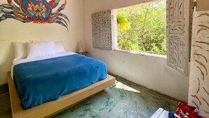 A room with a bed, a wall mural, a window with a view, and a basket of snacks. - Beco do Pescador (Porto Seguro)