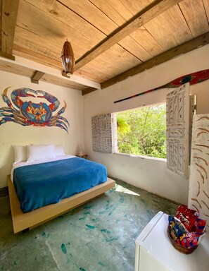 A room with a bed, a wall mural, a window with a view, and a basket of snacks. - Beco do Pescador (Porto Seguro)