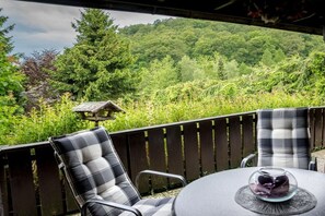 Eine Terrasse mit zwei Stühlen und einem Tisch mit Blick auf eine üppige, grüne Landschaft.
